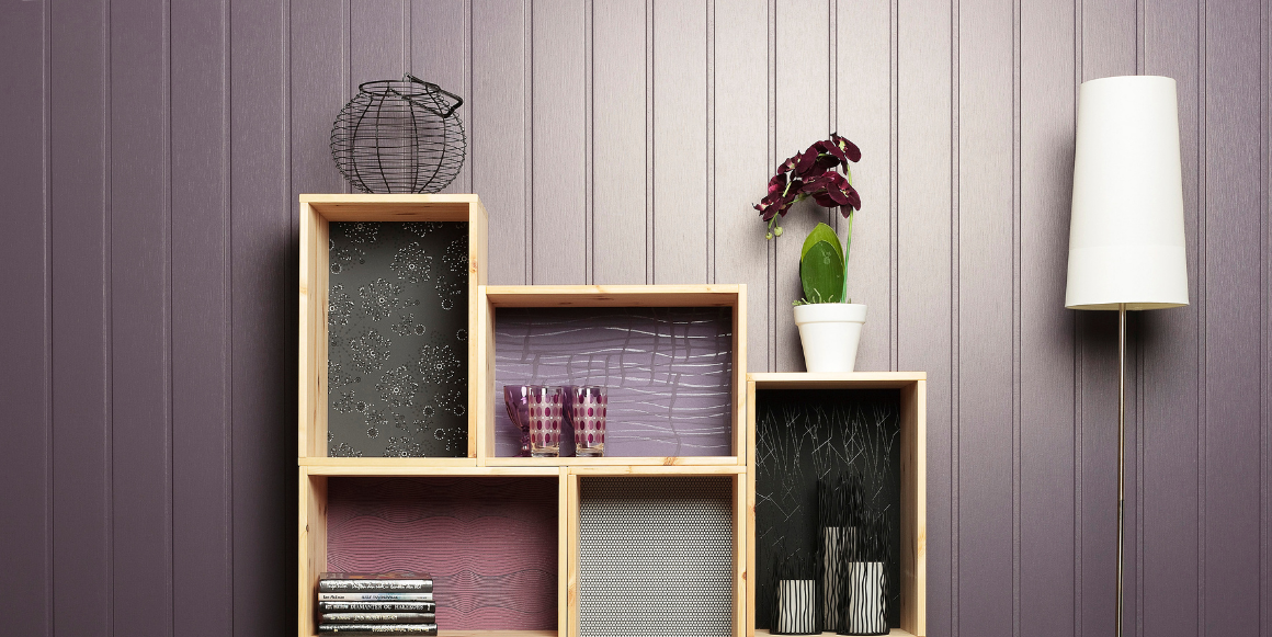 vegg med lilla veggplate i panel med bokhylle laget av hobbyplater med interiørartikler på. 