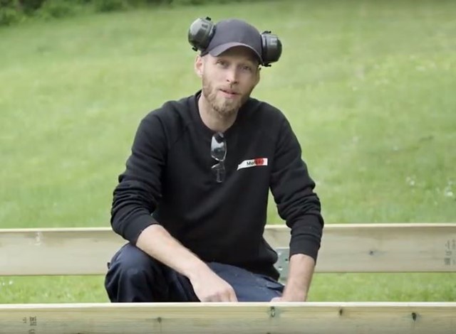 Mann i sort genser bygger rammeverk til terrasse