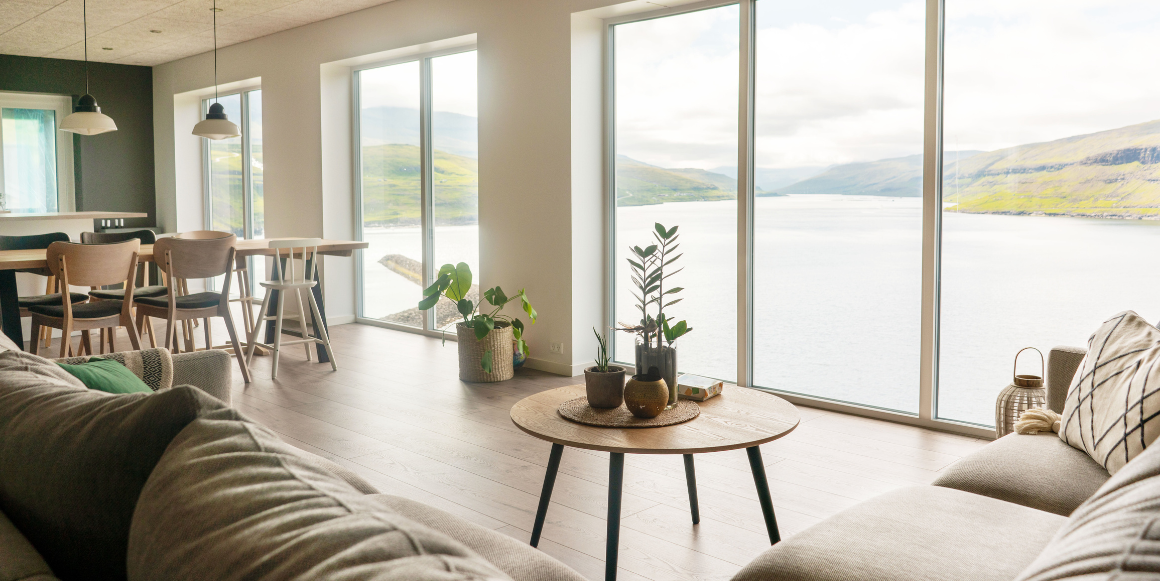 bilde av stue med en rekke store vinduer som gir utsikt til nordisk landskap,