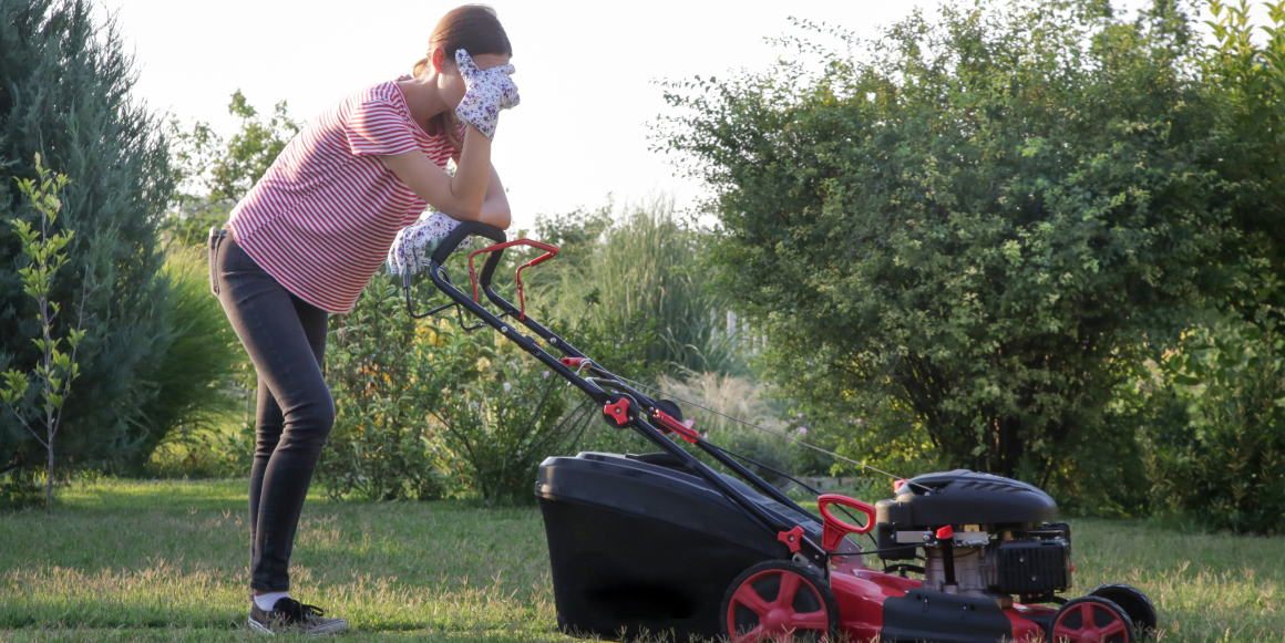 Kvinne som står lent over en ødelagt gressklipper