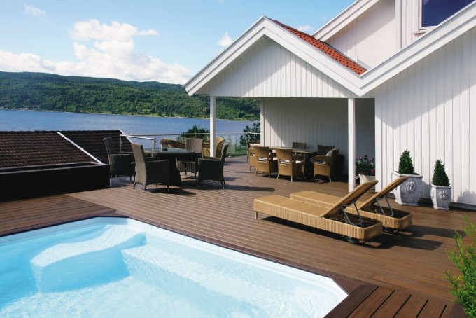 Flott brun terrasse rundt basseng med utsikt