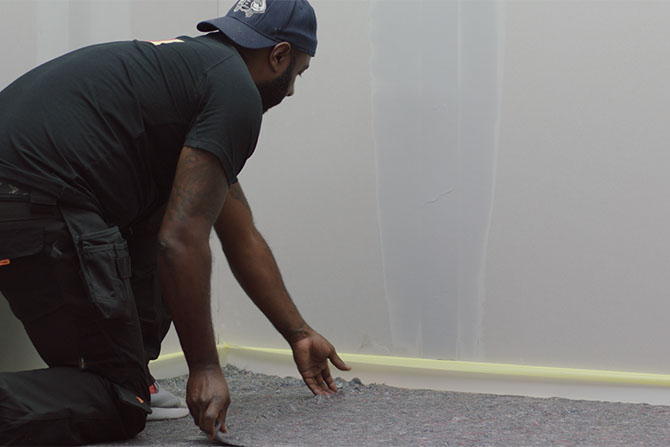 Maler legger dekkfilt på gulvet før maling av vegg