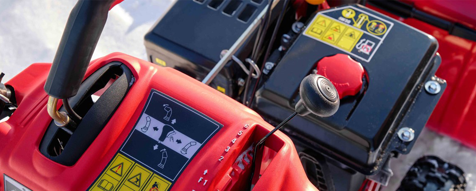 Nærbilde av sort og rød snøfreser med motor.