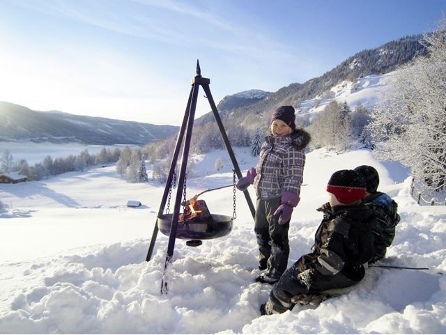 Barn ute i snøen ved siden av en bålpanne