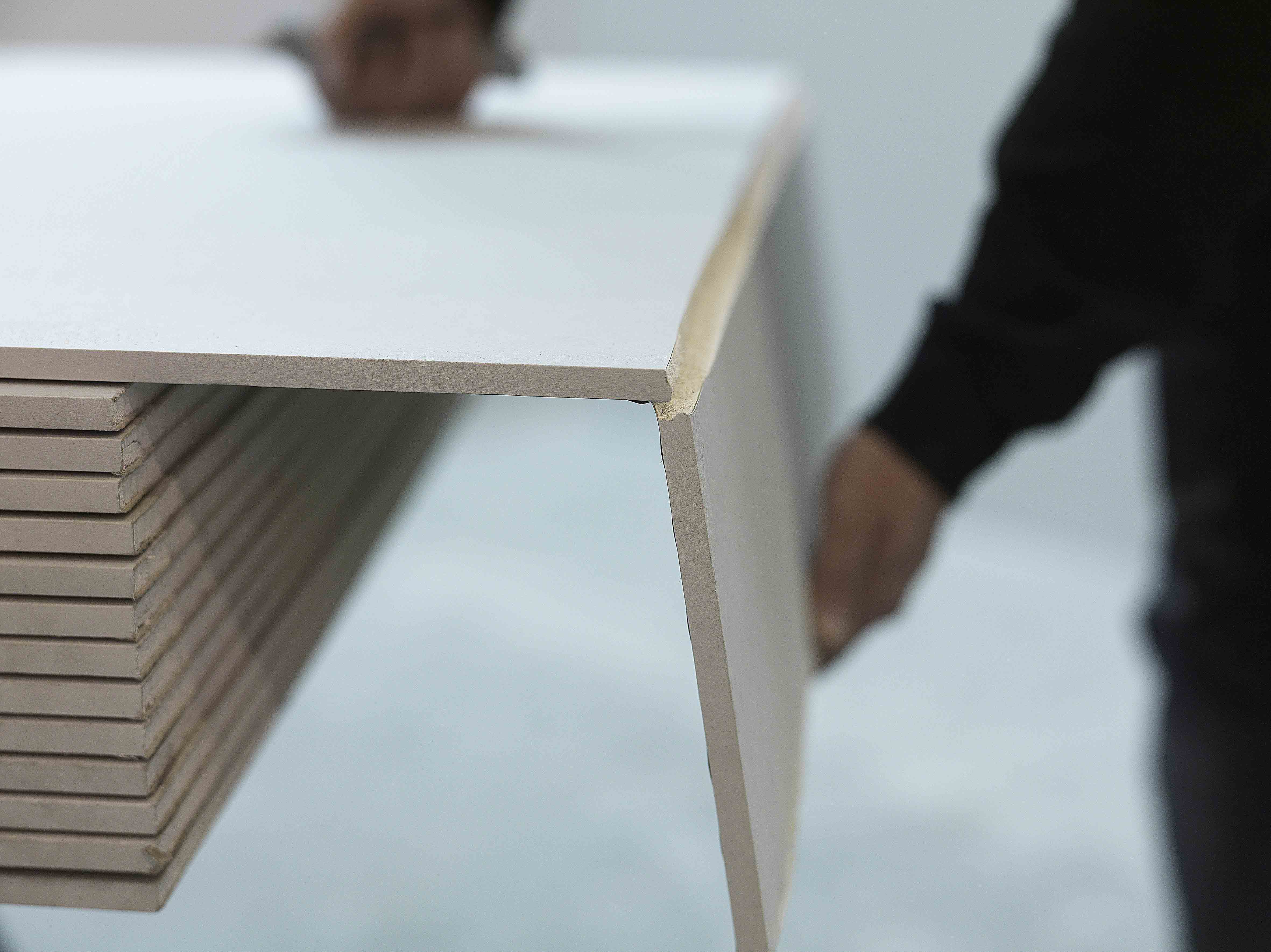 To hender knekker av en gipsplate etter at den er risset med tapetkniv.