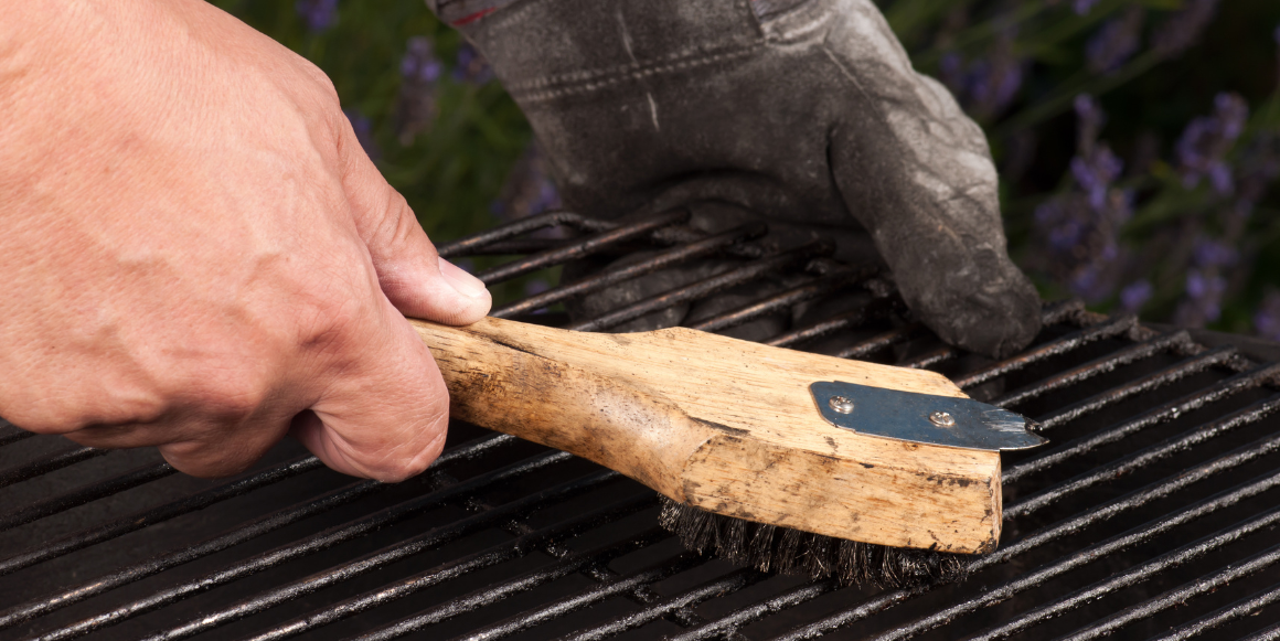 hånd som holder grillbørste for rengjøring av grillrist