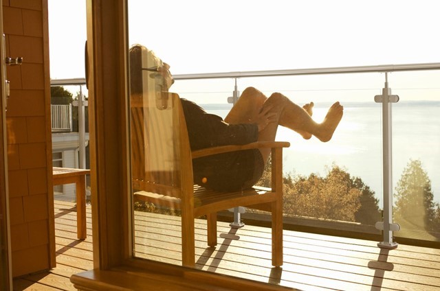 Mann sitter i en terrasse med føttene på terrasserekkverk