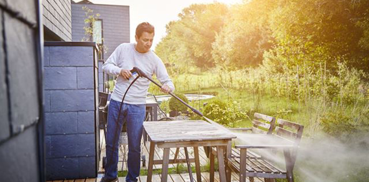 Mann som bruker en Nilfisk høytrykkspyler til å vaske en terrasse