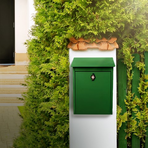 Grønn postkasse på mursøyle foran thuja.