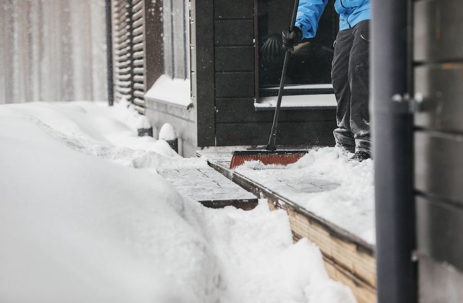 Bilde av en som soper snø vek fra terrassen.