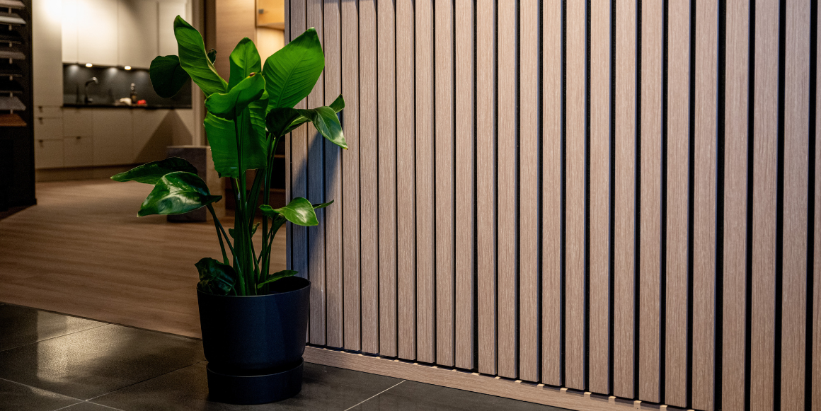 Spilevegg i moderne interiørdesign med en grønn plante i svart potte foran veggen, som gir en stilren og naturlig atmosfære.