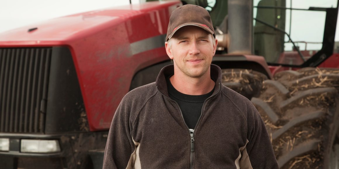 Mann som står foran en traktor.