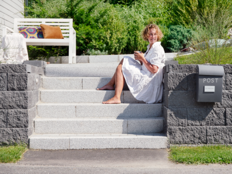 Dame som sitter i hagen der det er anrettet en trapp i belegningsstein Dame som sitter i hagen der det er anrettet en trapp i belegningsstein