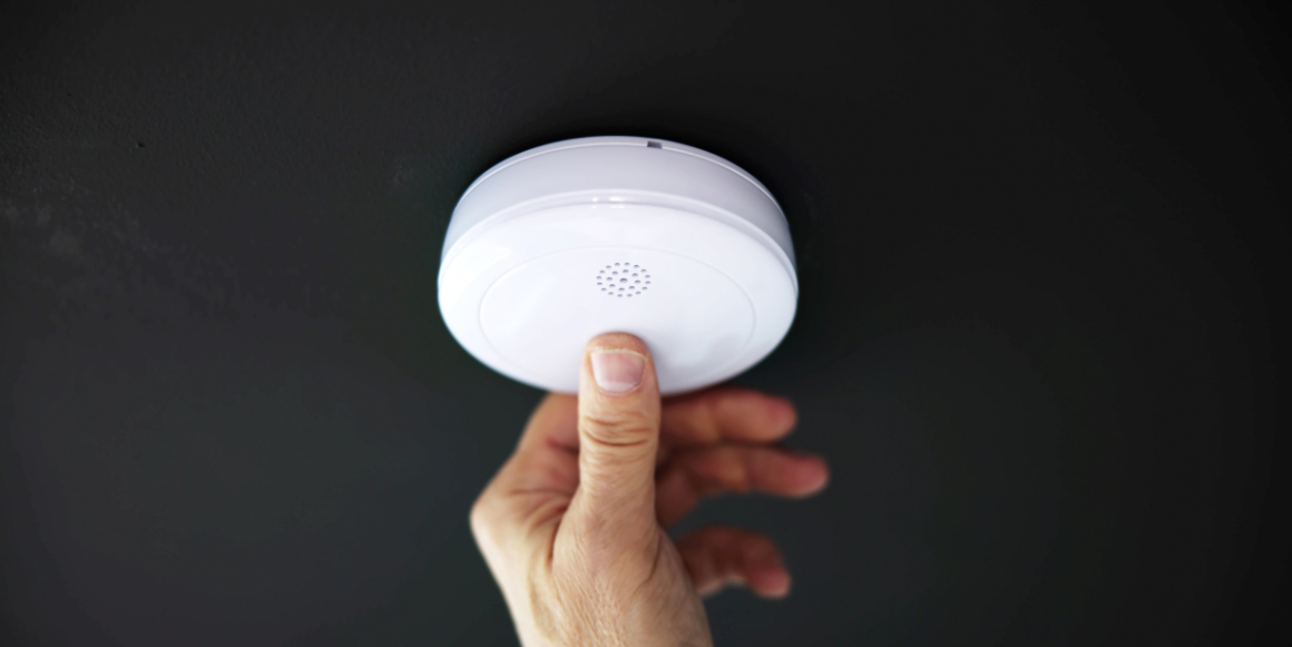 Hånd som tester røykvarsleren