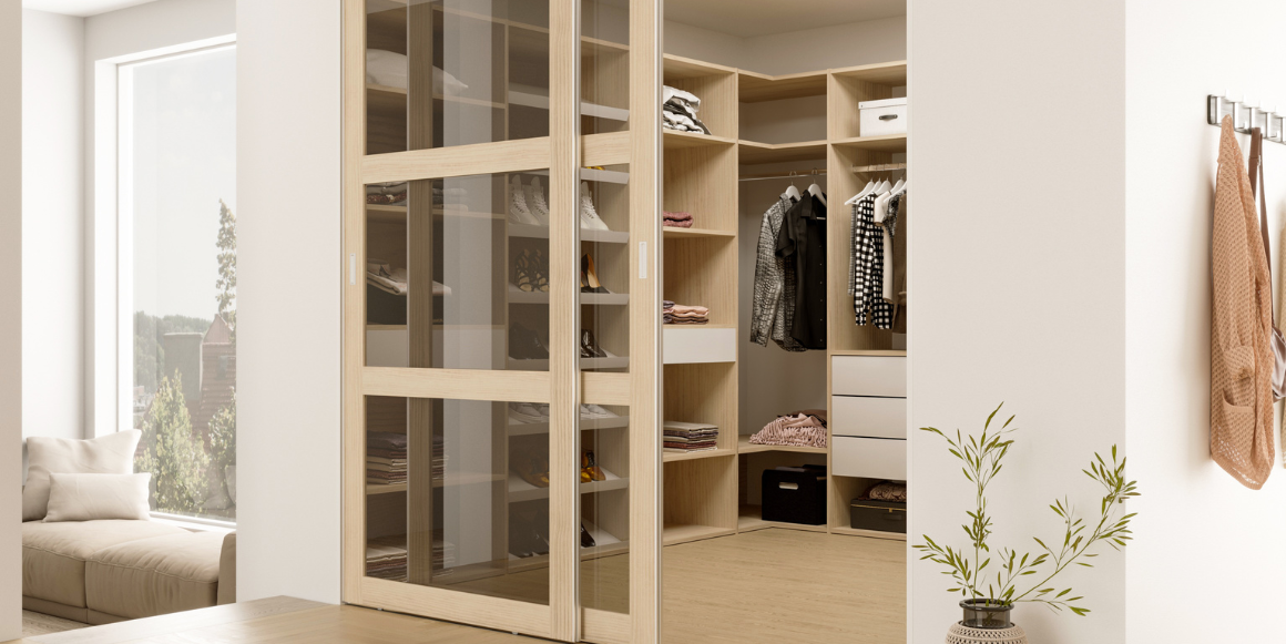 Lyst soverom med skyvedørsløsning inn til et lite walk in closet med innredning i lyst treverk. 