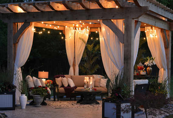 En pergola med koselig sofa, kaffebord og lyselenke på kveldstid En pergola med koselig sofa, kaffebord og lyselenke på kveldstid