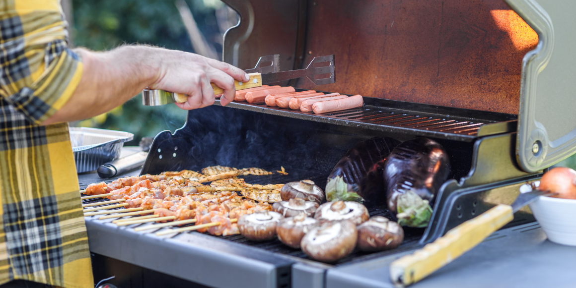 Mann som griller kjøtt og grønnsaker på en gassgrill Mann som griller kjøtt og grønnsaker på en gassgrill