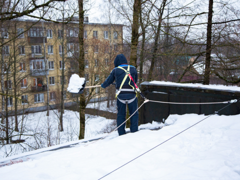 mann som måker snø av tak på hus i et borettslag mann som måker snø av tak på hus i et borettslag