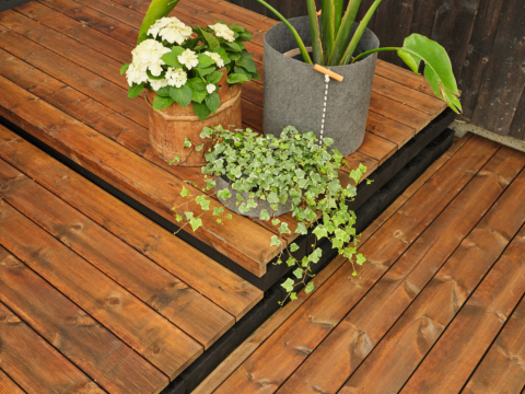Brun terrassebord bygd i ulike høyder med planter i bakgrunnen Brun terrassebord bygd i ulike høyder med planter i bakgrunnen