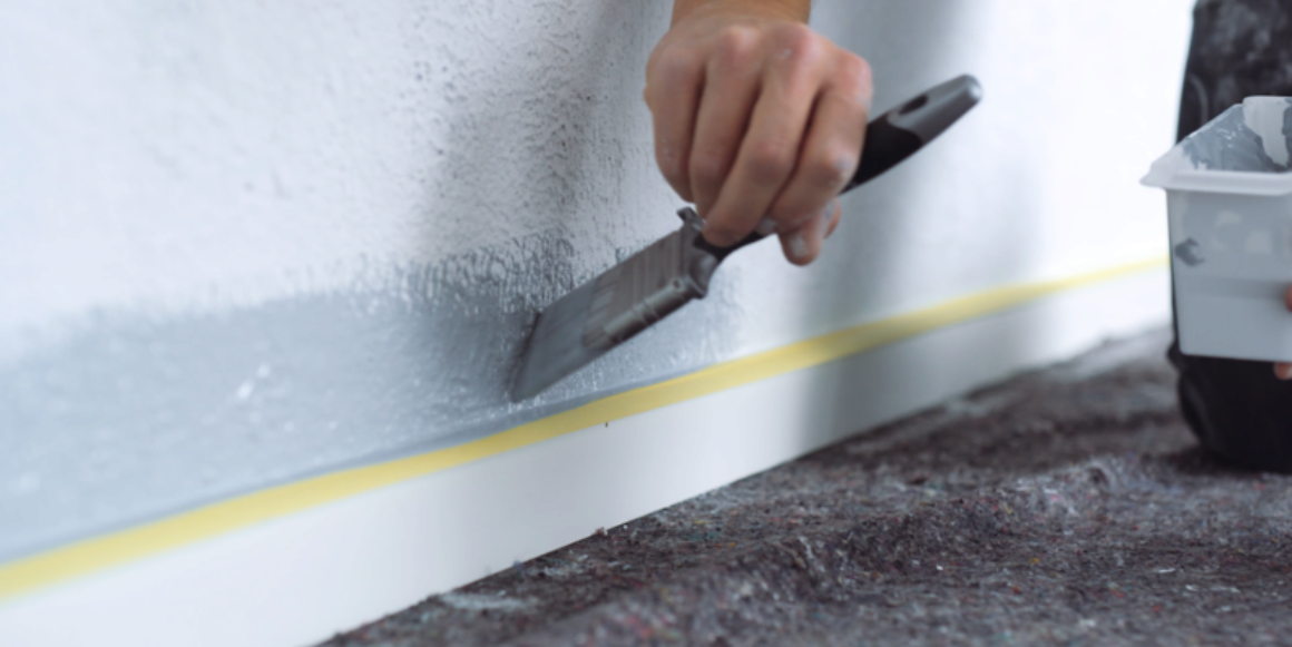 person som maler med en pensel med skrå bust for å få en bedre vinkel ved maling nær list.